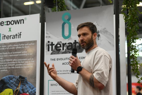 110824_8 Wege zur abfallfreien Zukunft_Iteratif Mann auf Messe vor Plakat mit Mikrofon