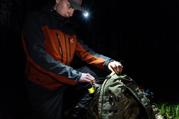 111524_ISPO Award Winner 2024: Fenix SW05R RED_Rucksack Mann mit Lampe an der Cap schaut in seinen Rucksack