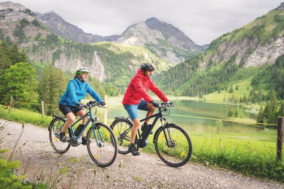 E-Bikes von Bosch Ein paar fährt mit dem Rad an einem Seeufer entlang